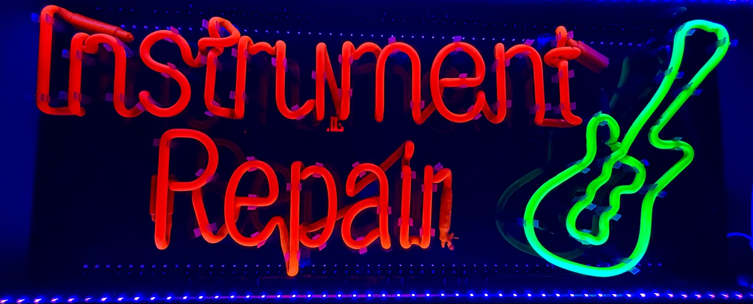 Handmade neon sign reading Instrument Repair with a glowing green guitar